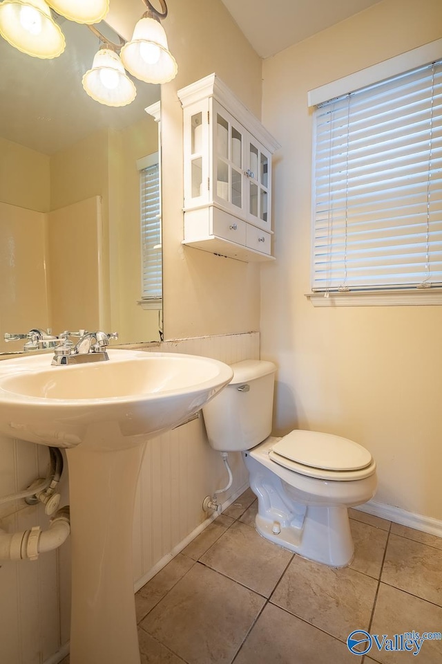 bathroom with a sink, baseboards, toilet, and tile patterned flooring