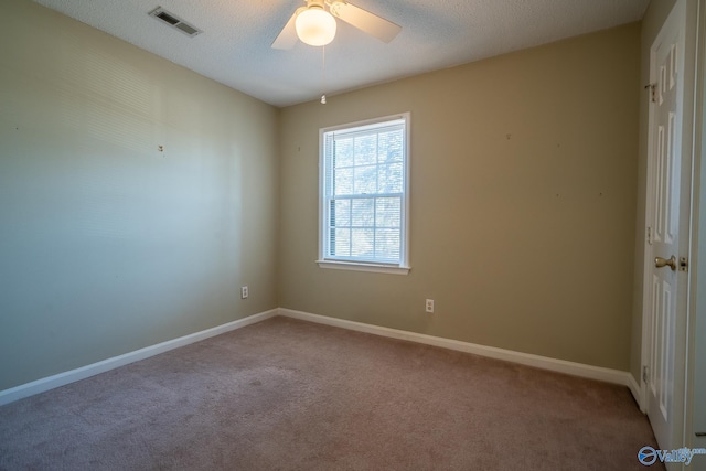 empty room featuring visible vents, carpet floors, a textured ceiling, and baseboards