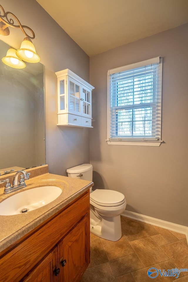 half bath with toilet, vanity, and baseboards