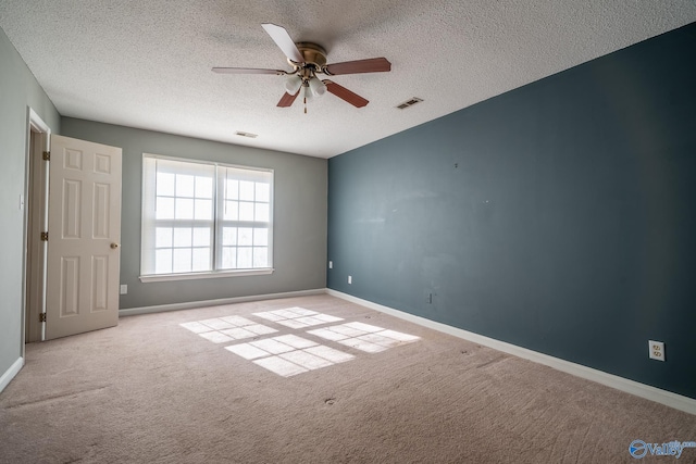 carpeted spare room with a ceiling fan, baseboards, visible vents, and a textured ceiling