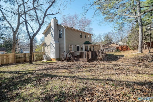 back of property with a deck, fence private yard, and a chimney