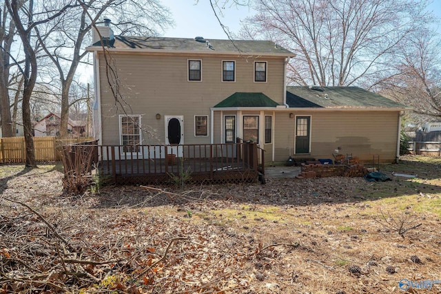 back of property with a chimney, a wooden deck, and fence