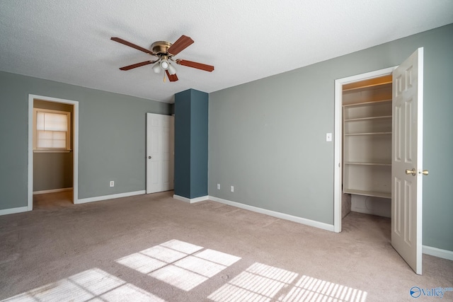 unfurnished bedroom featuring light colored carpet, a walk in closet, and baseboards