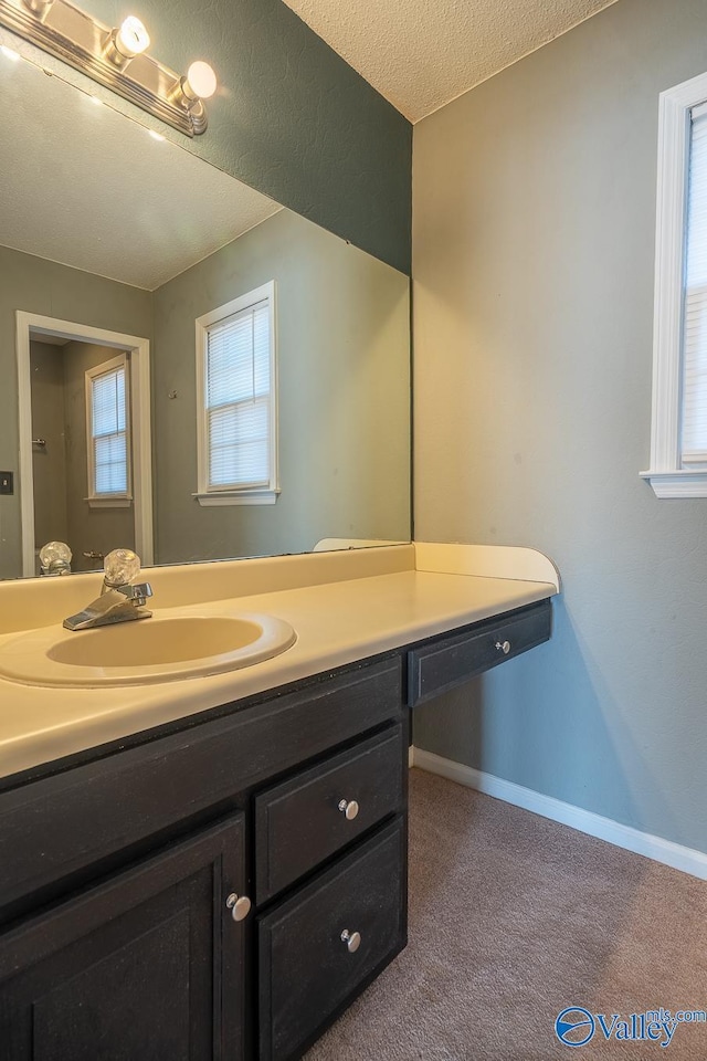 bathroom with a textured ceiling, vanity, and baseboards