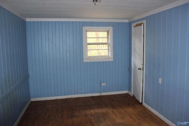 unfurnished room featuring dark hardwood / wood-style floors and wood walls