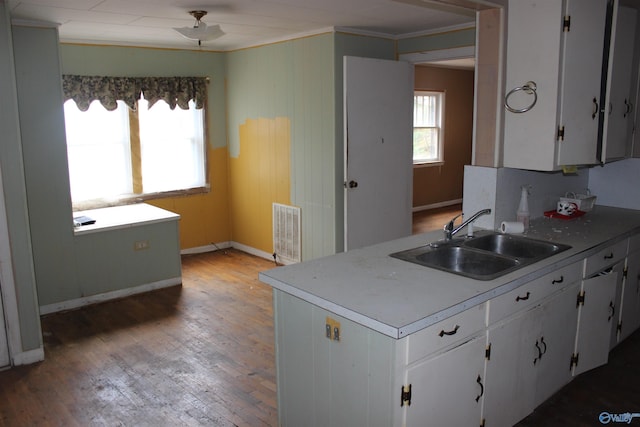 kitchen featuring crown molding, white cabinetry, sink, and wood-type flooring