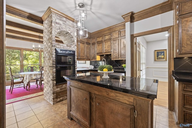 kitchen featuring a kitchen island, backsplash, decorative light fixtures, light tile patterned floors, and black double oven