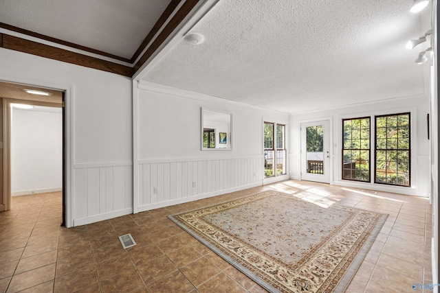 unfurnished living room featuring crown molding, a textured ceiling, and tile patterned flooring