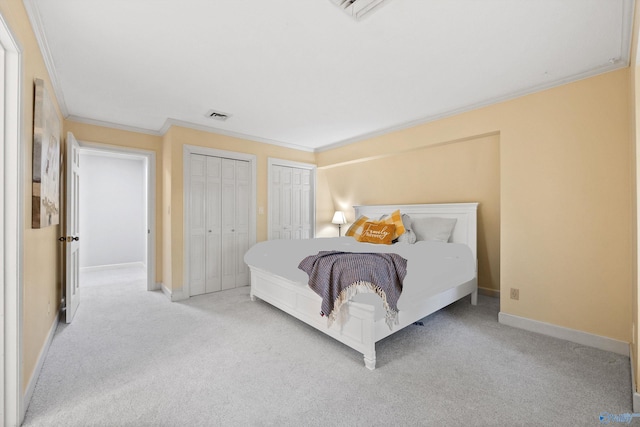 bedroom with light carpet, crown molding, and two closets