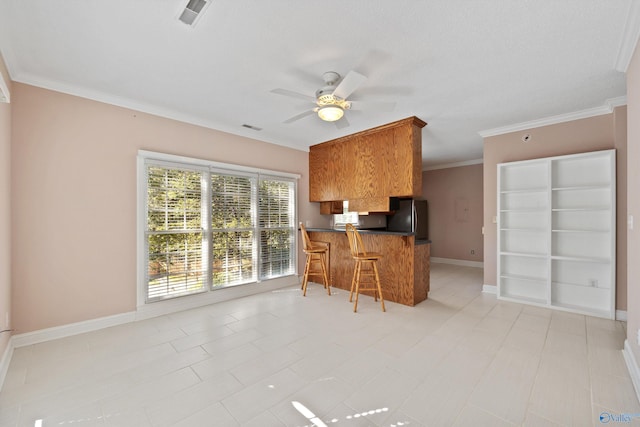 kitchen featuring kitchen peninsula, light tile patterned floors, a kitchen breakfast bar, stainless steel refrigerator, and ornamental molding