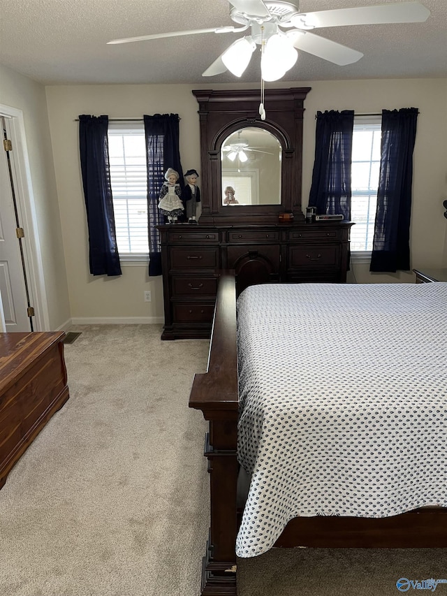 carpeted bedroom with multiple windows, a textured ceiling, and ceiling fan