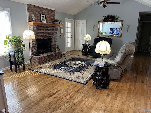 living room with ceiling fan, wood-type flooring, a fireplace, and vaulted ceiling