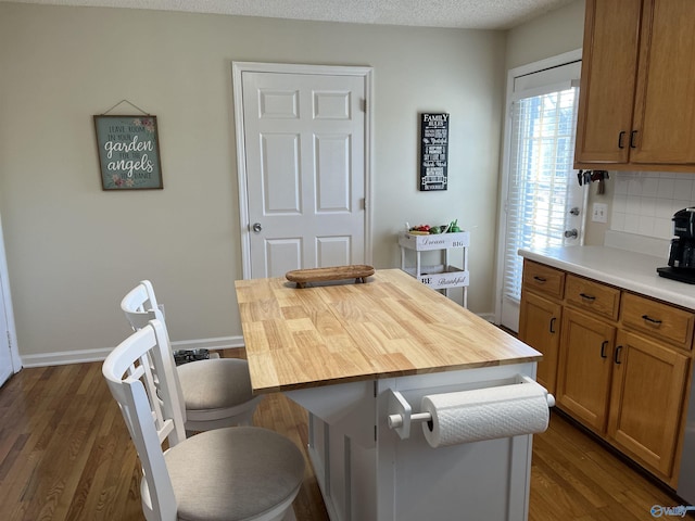 kitchen featuring a center island, dark wood-type flooring, wood counters, a textured ceiling, and decorative backsplash