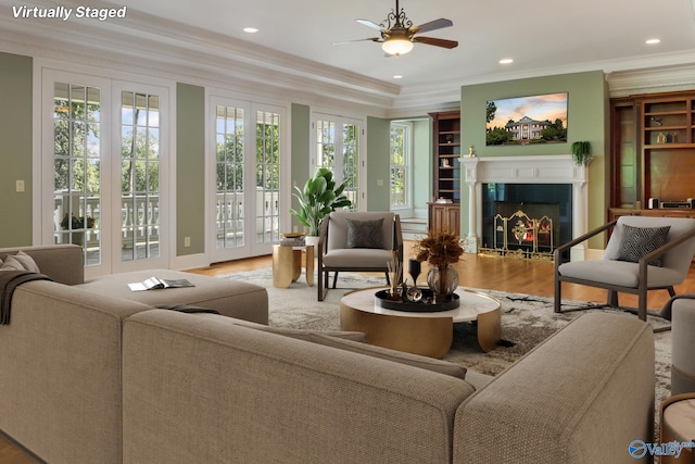 living room with ceiling fan, hardwood / wood-style floors, ornamental molding, and built in shelves