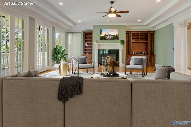 living room with hardwood / wood-style floors, ornamental molding, decorative columns, ceiling fan, and a premium fireplace