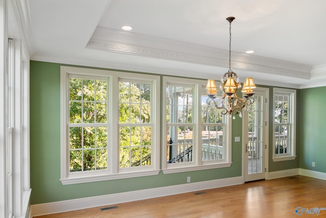 interior space with a wealth of natural light, wood-type flooring, and a chandelier