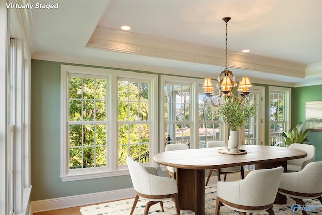 dining area featuring a raised ceiling, crown molding, a notable chandelier, and a healthy amount of sunlight