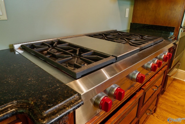 interior details featuring dark stone countertops and light hardwood / wood-style flooring