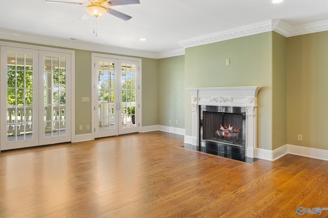 unfurnished living room featuring hardwood / wood-style floors, ornamental molding, french doors, a high end fireplace, and ceiling fan