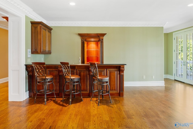 bar featuring light hardwood / wood-style flooring, crown molding, and french doors