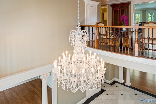 hallway with tile patterned flooring, a notable chandelier, and decorative columns