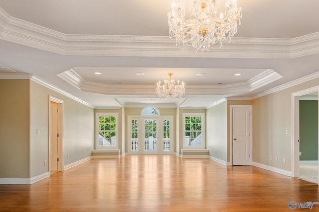 spare room with a raised ceiling, crown molding, and wood-type flooring