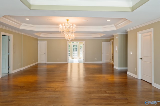 empty room with a notable chandelier, crown molding, a raised ceiling, and dark hardwood / wood-style flooring