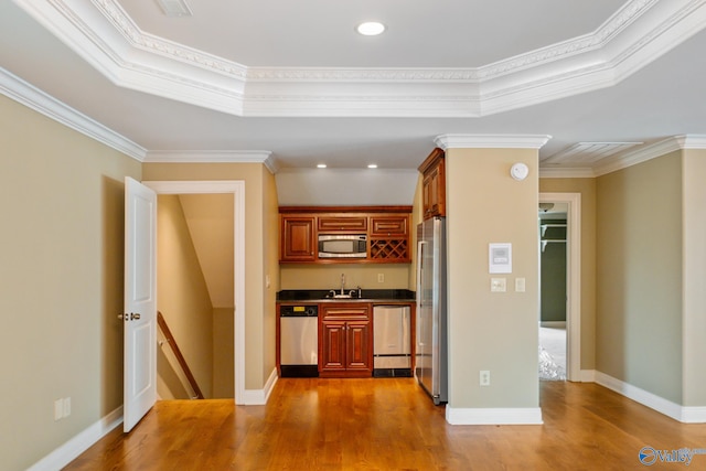 kitchen with appliances with stainless steel finishes, sink, ornamental molding, and light hardwood / wood-style flooring