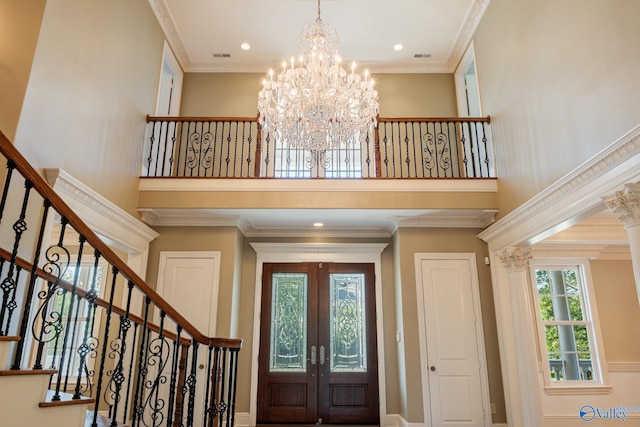 entryway featuring a high ceiling, crown molding, a chandelier, and french doors