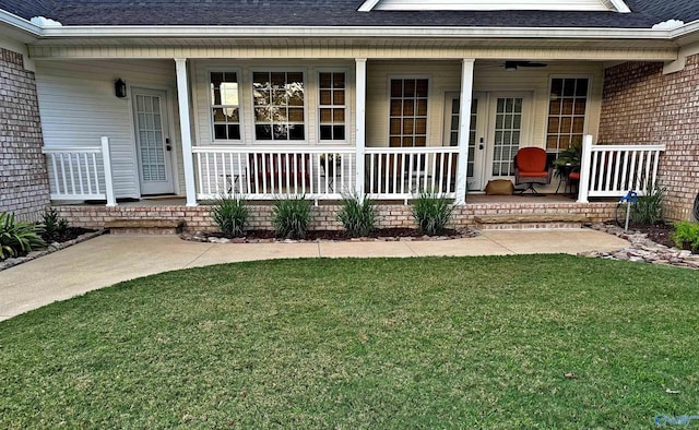 doorway to property with a porch, a yard, and ceiling fan