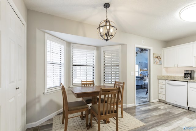 dining space with an inviting chandelier, a textured ceiling, and light wood-type flooring