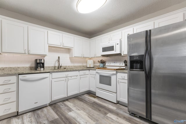 kitchen featuring white cabinetry, sink, light wood-type flooring, light stone countertops, and white appliances