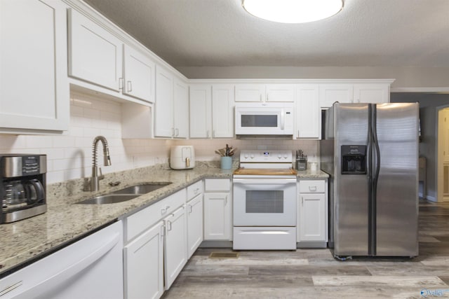 kitchen with white cabinetry, sink, and white appliances