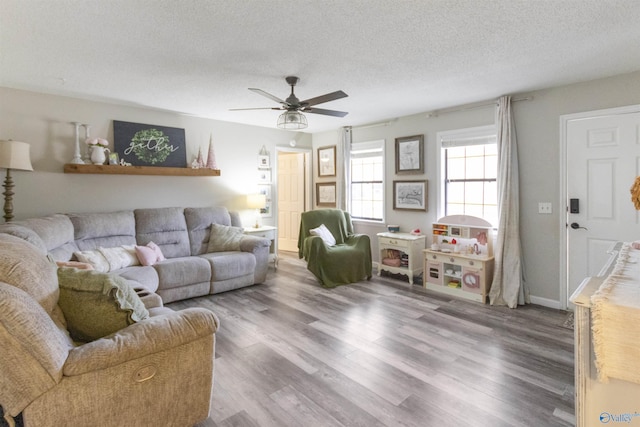 living room featuring ceiling fan, wood-type flooring, and a textured ceiling