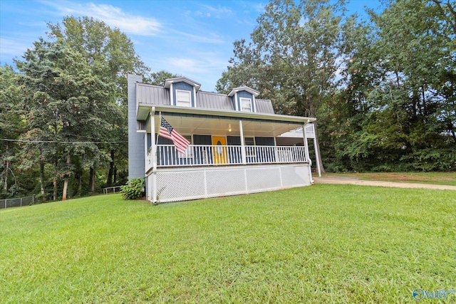 view of front of house featuring covered porch, metal roof, a chimney, and a front yard