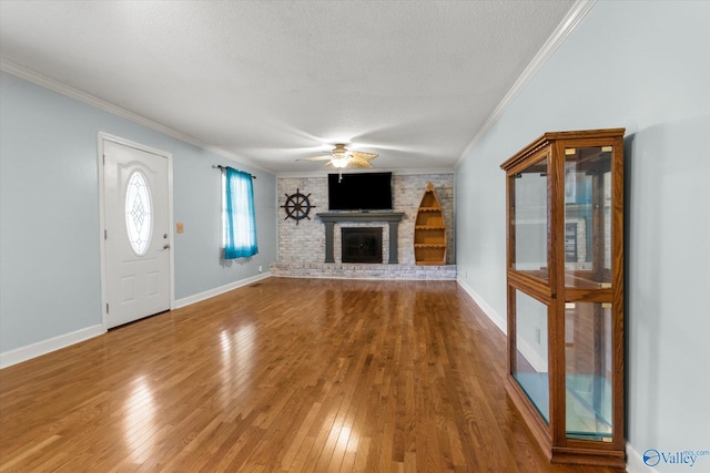 unfurnished living room featuring a brick fireplace, crown molding, a textured ceiling, and hardwood / wood-style floors