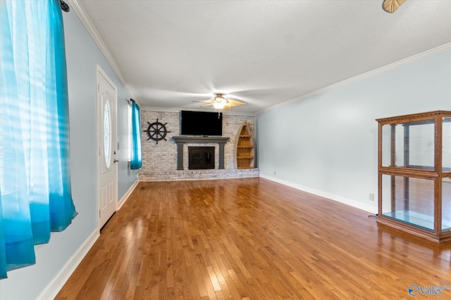 unfurnished living room with baseboards, wood-type flooring, ceiling fan, ornamental molding, and a fireplace