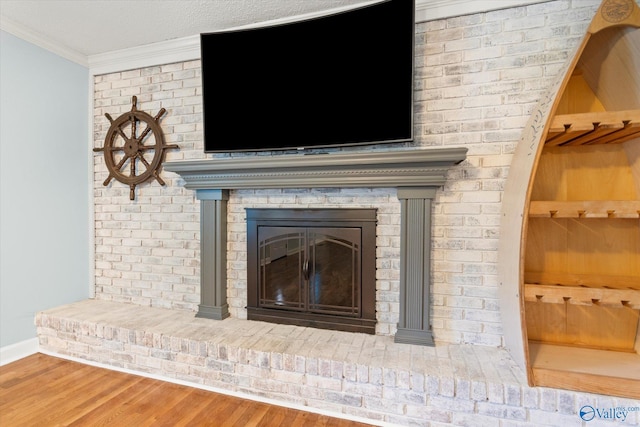 details featuring wood finished floors, baseboards, built in features, a brick fireplace, and crown molding