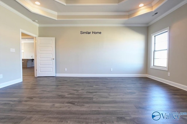 empty room with ornamental molding, dark hardwood / wood-style flooring, and a raised ceiling