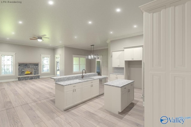 kitchen with hanging light fixtures, white cabinetry, sink, and a center island with sink