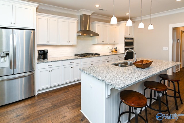 kitchen featuring a sink, dark wood-type flooring, appliances with stainless steel finishes, crown molding, and wall chimney exhaust hood