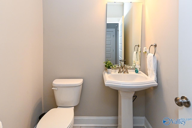 bathroom with toilet and baseboards