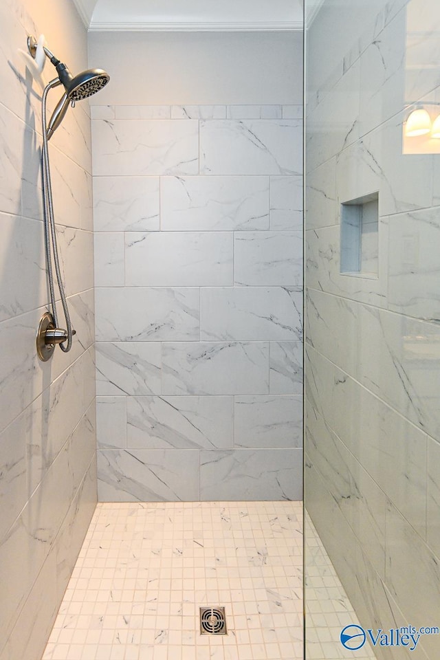 bathroom with a tile shower and crown molding