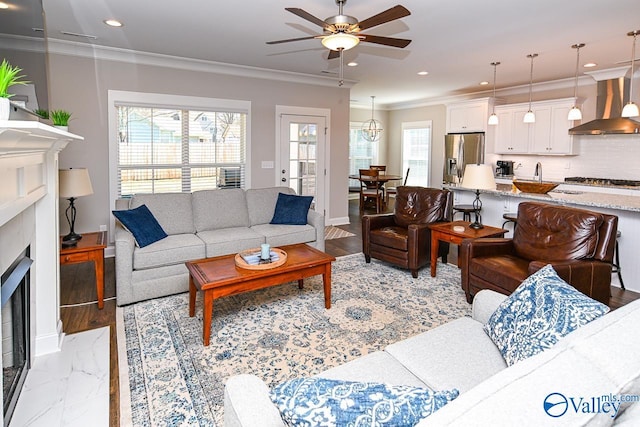 living area with crown molding, baseboards, ceiling fan, recessed lighting, and a fireplace