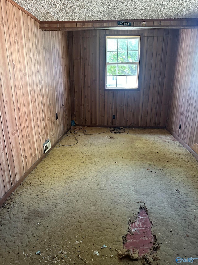 spare room with wooden walls and a textured ceiling