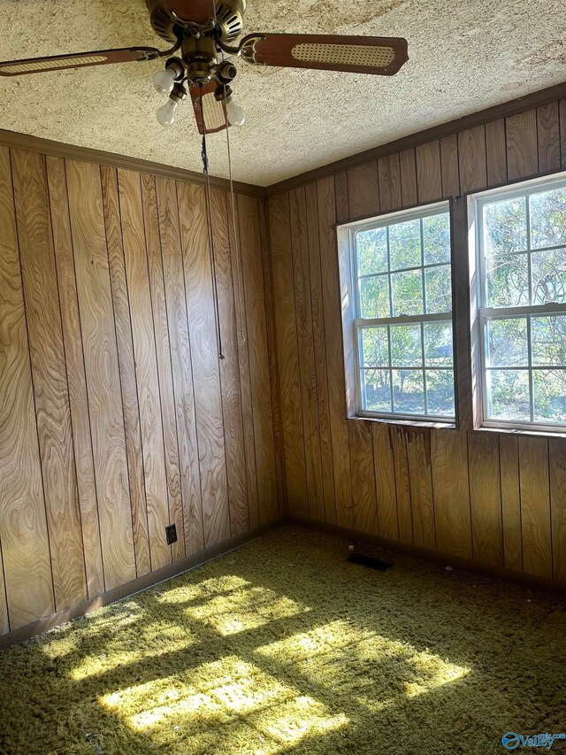 spare room featuring wood walls, a textured ceiling, and ceiling fan