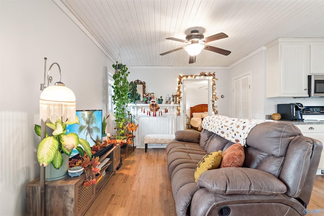 living area featuring light wood finished floors, ceiling fan, and crown molding