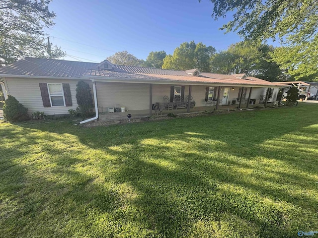 back of house with metal roof and a lawn