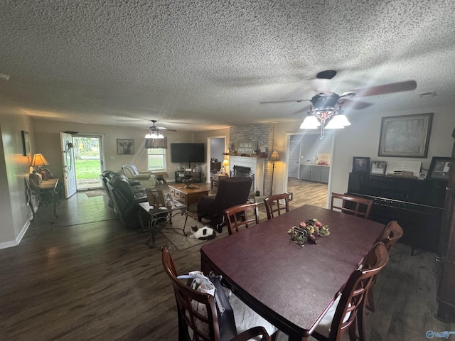 dining room with ceiling fan, a brick fireplace, and wood finished floors