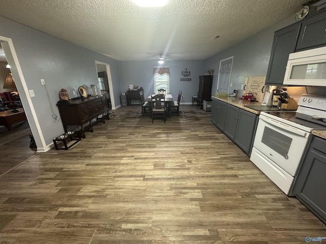 kitchen with gray cabinetry, a textured ceiling, dark wood-style flooring, and white appliances